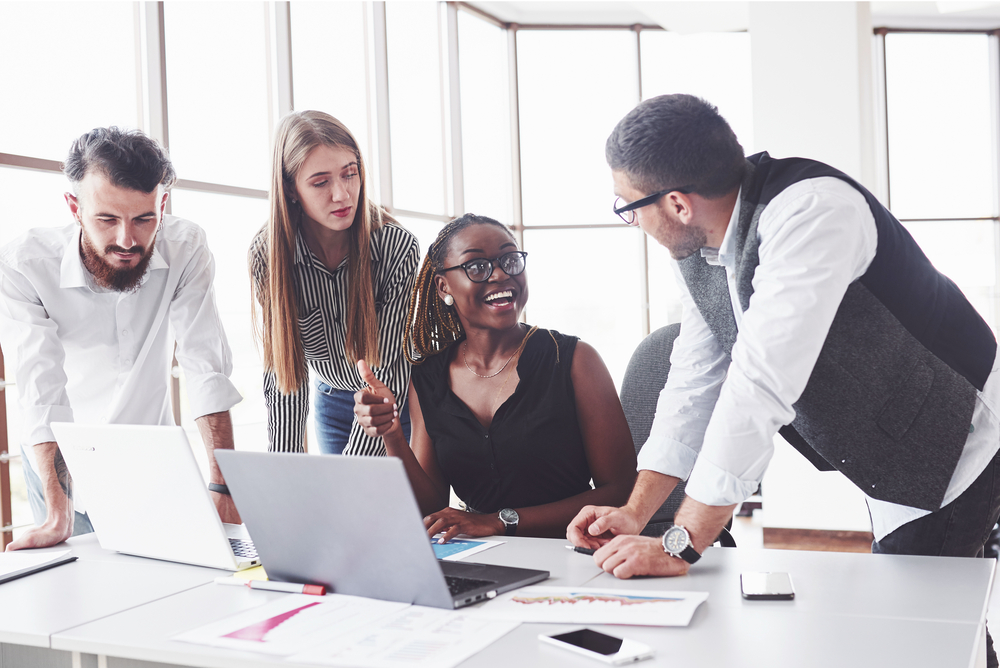 That will be easy. Four multiracial employee have work in the office using the laptop on table